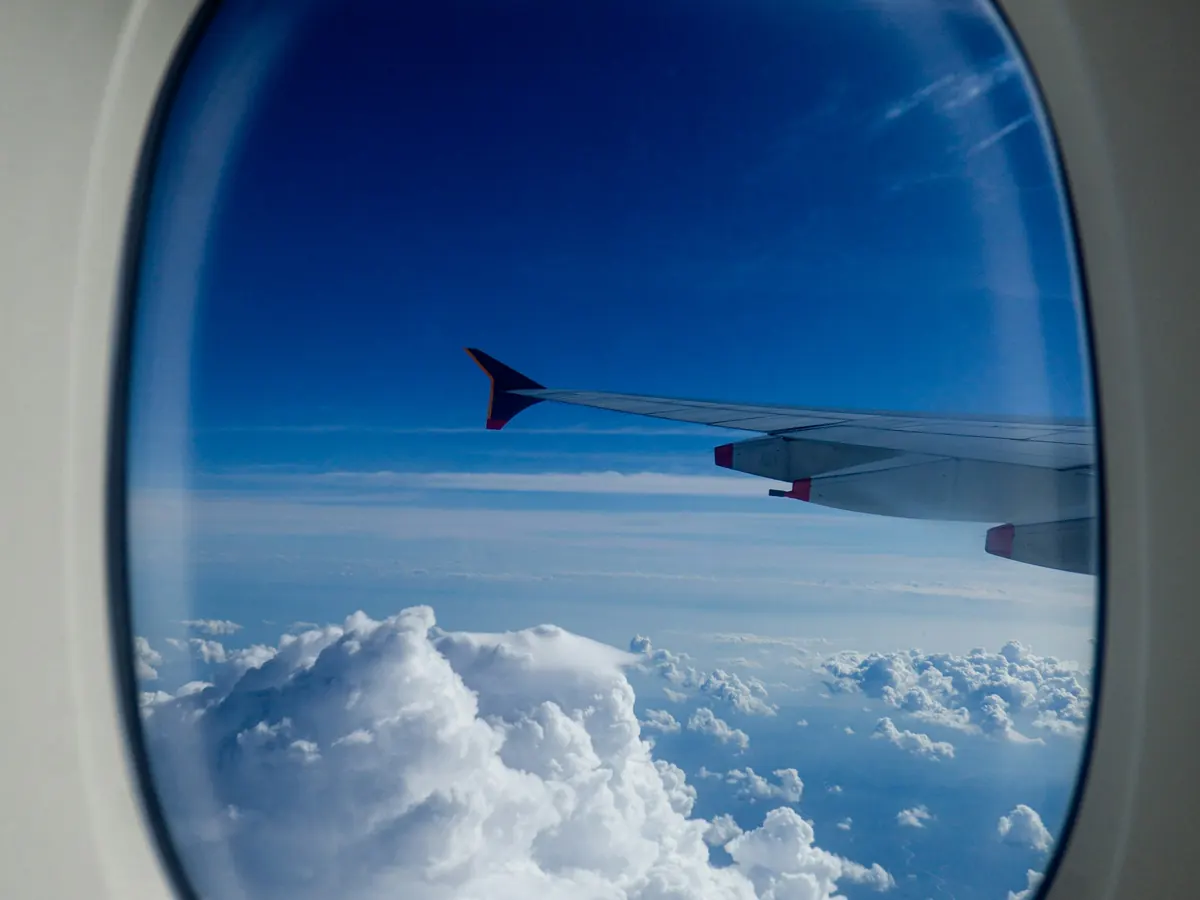 Aircraft wing over bright cloud seen from a cabin window