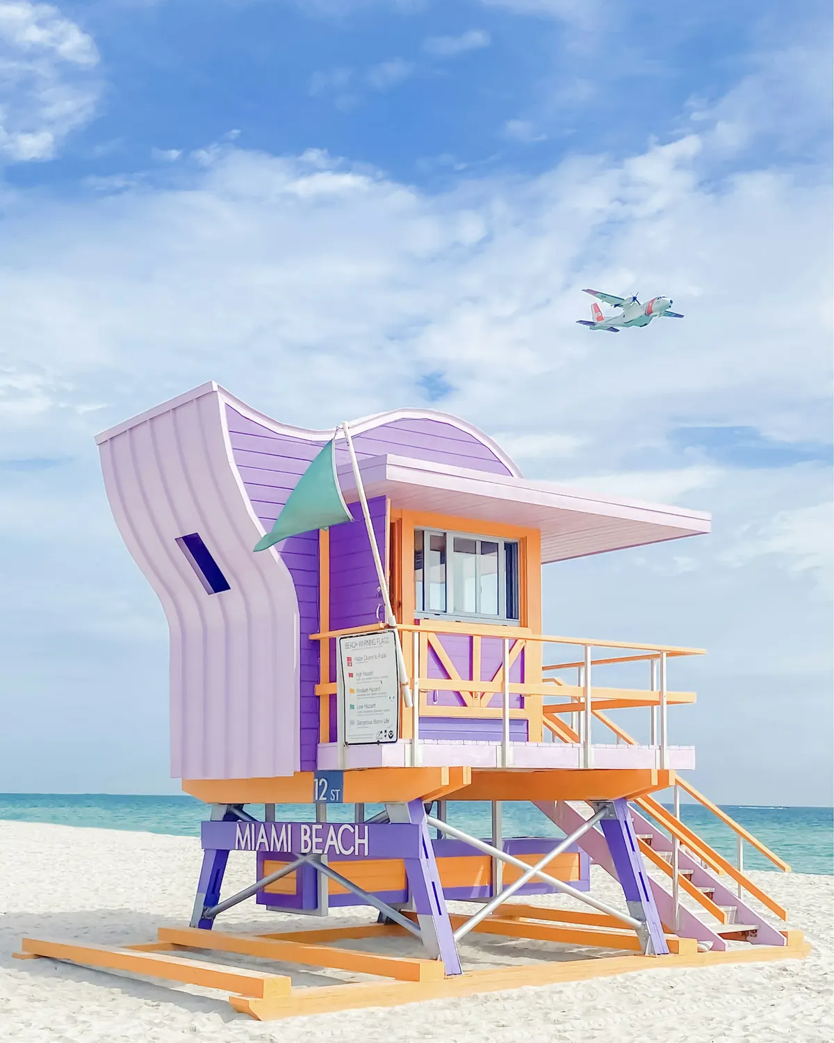 Pastel lifeguard stand on Miami Beach with a plane passing overhead